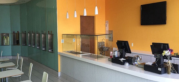 a Gelato shop with yellow & green wall & 4 stoelting frozen drink machines inside the wall & a cash register
