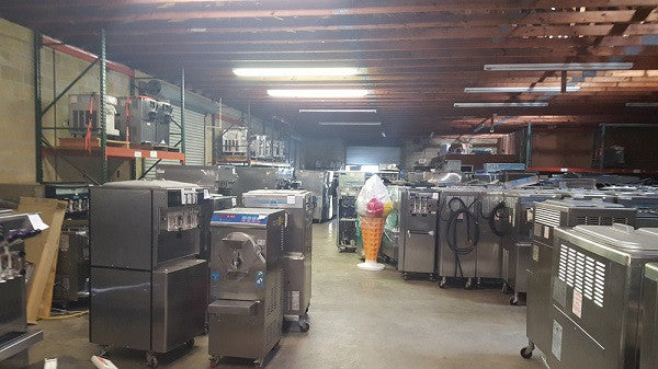 frozen drink & gelato machine warehouse with many ice cream machines & a giant plastic ice cream cone